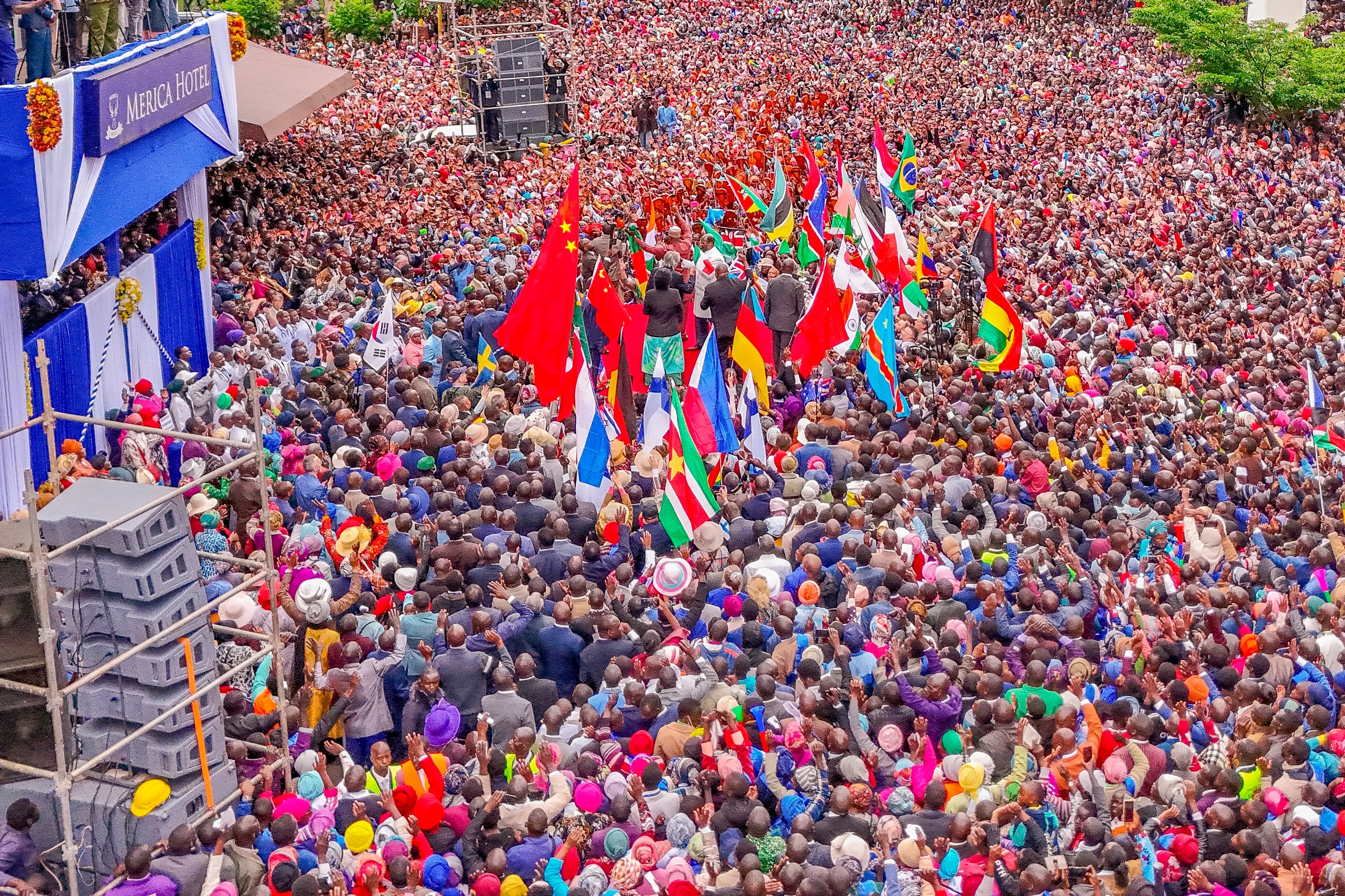 Aerial view of a vast crowd in Nakuru carrying the flags of many nations.